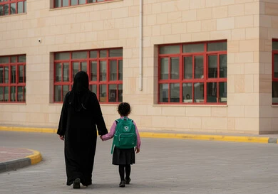 الشعور بالأمان والحب مع الآباء، موسم العودة للمدارس في السعودية، مفهوم الاعتناء بالأبناء والاهتمام بهم، بنت عربية خليجية سعودية ترتدي الزي المدرسي تضع الحقيبة على ظهرها وتمسك بيد والدتها للدخول إلى المدرسة، الاستعداد للعام الدراسي