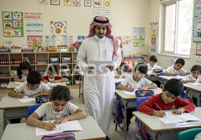 جودة التعليم في السعودية، المشاركة الفعالة للطلاب مع المدرسين، حوارات ونقاشات بين الاستاذة والطلاب، معلم عربي خليجي سعودي يرتدي الثوب التقليدي والشماغ يقوم بمناقشة الدروس مع طلابه، التربية والتعليم بالمناهج المقررة للتلاميذ، العودة إلى المدارس