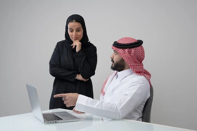 تبادل الخبرات والمعلومات لتحقيق الاهداف, الحوار و النقاش بين الزملاء، بيئة العمل المريحة في الشركات السعودية، بورتريه لموظفان عربيان خليجيان سعوديان يعملان في مكتبهم داخل مقر الشركة، استخدام الحاسب والتقنية في مجال الاعمال، خلفية رمادية