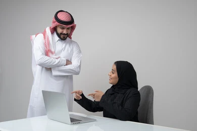 الحوار و النقاش بين الزملاء، بيئة العمل المريحة في الشركات السعودية، تبادل الخبرات والمعلومات لتحقيق الاهداف, بورتريه لموظفان عربيان خليجيان سعوديان يعملان في مكتبهم داخل مقر الشركة، استخدام الحاسب والتقنية في مجال الاعمال، خلفية رمادية