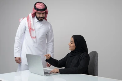 الحوار و النقاش بين الزملاء، بيئة العمل المريحة في الشركات السعودية، تبادل الخبرات والمعلومات لتحقيق الاهداف, بورتريه لموظفان عربيان خليجيان سعوديان يعملان في مكتبهم داخل مقر الشركة، استخدام الحاسب والتقنية في مجال الاعمال، خلفية رمادية