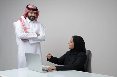 بيئة العمل المريحة في الشركات السعودية، الحوار و النقاش بين الزملاء، تبادل الخبرات والمعلومات لتحقيق الاهداف, بورتريه لموظفان عربيان خليجيان سعوديان يعملان في مكتبهم داخل مقر الشركة، استخدام الحاسب والتقنية في مجال الاعمال، خلفية رمادية