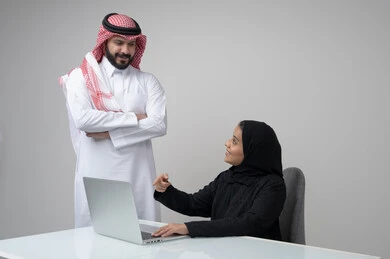 بيئة العمل المريحة في الشركات السعودية، الحوار و النقاش بين الزملاء، تبادل الخبرات والمعلومات لتحقيق الاهداف, بورتريه لموظفان عربيان خليجيان سعوديان يعملان في مكتبهم داخل مقر الشركة، استخدام الحاسب والتقنية في مجال الاعمال، خلفية رمادية