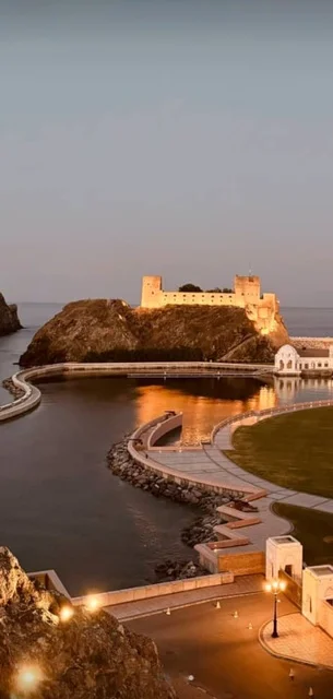 معلم وحصن عسكري تاريخي، موقع استراتيجي مهم مطل على خليج عمان, قلعة الميراني المبنية من الطين في سلطنة عمان المضاءة في وقت الليل ,التصميم والفن الهندسي المعماري على الطراز القديم، معلم ومزار سياحي تراثي مشهور في مدينة مسقط القديمة.