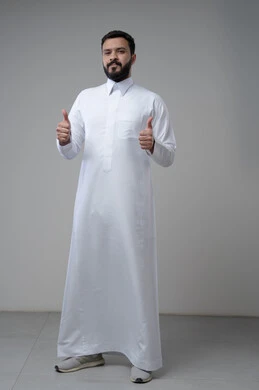 Thumbs up, looking at camera with expressions of admiration and satisfaction, portrait of a Saudi Arabian Gulf man wearing traditional thobe looking at camera with gestures of acceptance and approval, full body photo, gray background