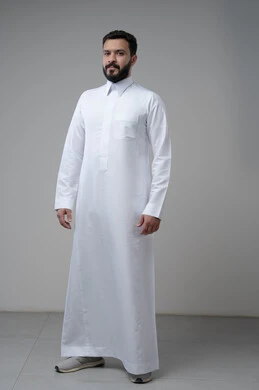  الاعتناء والاهتمام بالمظهر الخارجي، الوقوف بجدية وحزم، مفهوم الاناقة والرجولة، بورتريه لشاب عربي خليجي سعودي يرتدي الثوب التقليدي يقف باستقامة ينظر الى الكاميرا بتعابير الثقة بالنفس، الجسم بالطول الكامل، خلفية رمادية