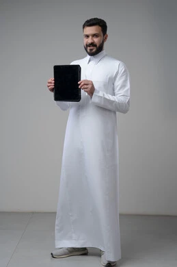 Blank black screen on tablet, browsing social media, using technology and modern technology, portrait of a Saudi Arabian Gulf man wearing traditional thobe holding a tablet in his hand looking at the camera with an expression of pleasure, full body image, gray background