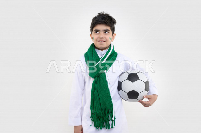 Portrait of a smiling Saudi Arabian Gulf Arab boy holding a soccer ball ...