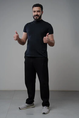 رفع اصابع الابهام الى الاعلى، النظر الى الكاميرا  بتعابير الاعجاب والرضا، بورتريه لرجل عربي خليجي سعودي يرتدي الزي الكاجوال ينظر الى الكاميرا بايماءات القبول والموافقة، صورة الجسم بالطول الكامل، خلفية رمادية