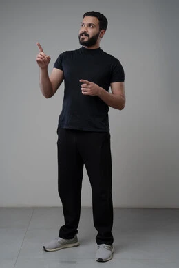 النظر الى الاعلى بتعابير التركيز، بورتريه لرجل عربي خليجي سعودي يرتدي الزي الكاجوال يشير بيده الى شيء ما، الدلالة على مكان معين، صورة الجسم بالطول الكامل، خلفية رمادية