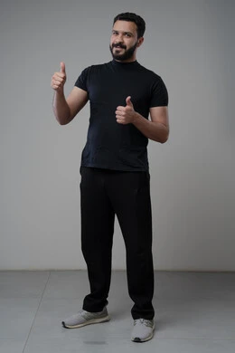 Thumbs up, looking at camera with expressions of admiration and satisfaction, portrait of a Saudi Arabian Gulf man in casual wear looking at camera with gestures of acceptance and approval, full body photo, gray background