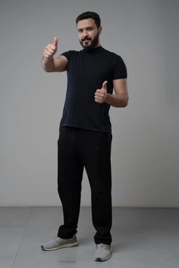 رفع اصابع الابهام الى الاعلى، النظر الى الكاميرا  بتعابير الاعجاب والرضا، بورتريه لرجل عربي خليجي سعودي يرتدي الزي الكاجوال ينظر الى الكاميرا بايماءات القبول والموافقة، صورة الجسم بالطول الكامل، خلفية رمادية