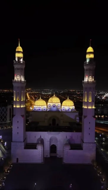 Worship and closeness to God, performing religious duties, modern Islamic architectural art of the mosques of Muscat Governorate, famous sacred Islamic religious places and landmarks in the Sultanate of Oman, the illuminated domes and minarets of the Mohammed Al-Amin Mosque at night in the Wilayat of Bausher