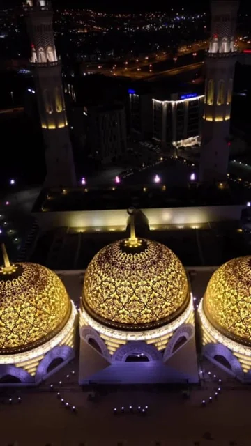 Famous Islamic religious holy places and landmarks in the Sultanate of Oman, worship and closeness to God, performing religious duties, modern Islamic architectural art of mosques in Muscat Governorate, an aerial photo of the illuminated domes of the Mohammed Al-Amin Mosque at night in the Wilayat of Bawshar