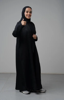 Expressions of approval and acceptance, looking at the camera with gestures of pleasure, satisfaction and admiration, portrait of a smiling veiled Saudi Arabian Gulf woman wearing an abaya, pointing thumbs up in a sign of excellence, full body length, white background