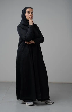 Gestures of thinking and contemplating something, portrait of a veiled Saudi Arabian Gulf woman wearing a black abaya, putting her hand on her face with gestures of contemplation, full-length body image, white background