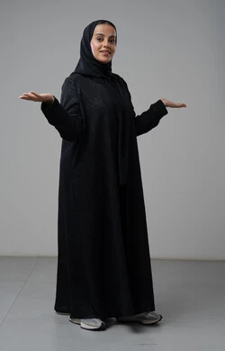 Gestures of ignorance, portrait of a veiled Saudi Arabian Gulf woman wearing a black abaya raising her hands in gestures of disapproval, full-length body image, white background
