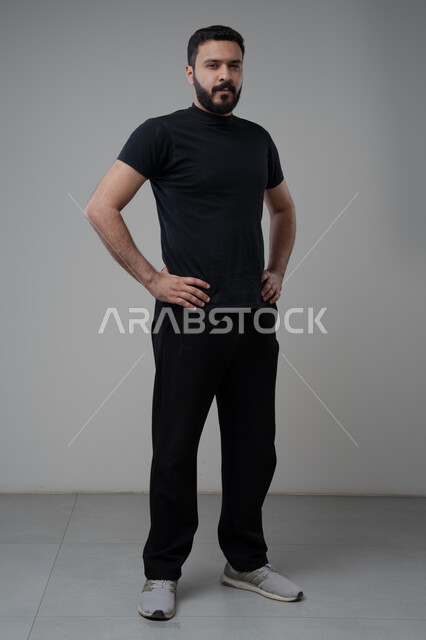  الاعتناء والاهتمام بالمظهر الخارجي، الوقوف بجدية وحزم، مفهوم الاناقة والرجولة، بورتريه لشاب عربي خليجي سعودي يرتدي الزي الكاجوال يقف باستقامة ينظر الى الكاميرا بتعابير الثقة بالنفس، الجسم بالطول الكامل، خلفية رمادية