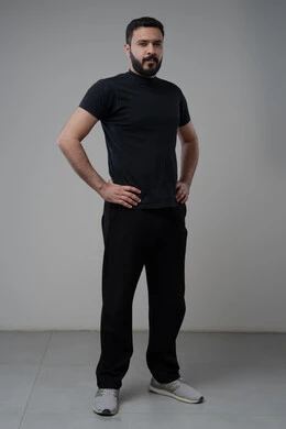 Taking care and attention to one's appearance, standing seriously and firmly, the concept of elegance and masculinity, a portrait of a young Saudi Arabian Gulf man wearing casual clothes, standing straight, looking at the camera with an expression of self-confidence, full-length body, gray background