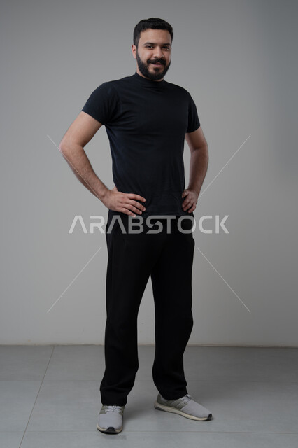  الاعتناء والاهتمام بالمظهر الخارجي، الوقوف بجدية وحزم، مفهوم الاناقة والرجولة، بورتريه لشاب عربي خليجي سعودي يرتدي الزي الكاجوال يقف باستقامة ينظر الى الكاميرا بتعابير الثقة بالنفس، الجسم بالطول الكامل، خلفية رمادية