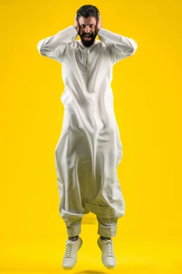 الشعور بالدهشة والذهول, تلقي اخبار سعيدة غير متوقعة، النظر إلى الكاميرا بايماءات الصدمة والتعجب والانبهار, التفاجؤ من موقف محدد، تذكر شيء ما، بورتريه لرجل عربي خليجي اماراتي يرتدي الكندورة يقفز عاليا ويضع يديه على رأسه، صورة لكامل الجسم، خلفية صفراء