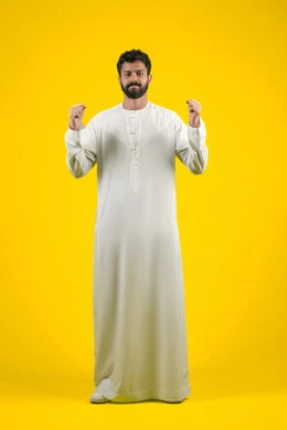 مفهوم التريث والتأني، الهدوء وطلب الإنتظار، ممارسة تمارين الاسترخاء، بورتريه لرجل عربي خليجي إماراتي يرتدي الكندورة البيضاء يرفع يديه بإيماءات الصبر، إمهال الوقت للقيام بشيء ما، صورة لكامل الجسم، خلفية صفراء