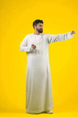 انشطة رياضية بدنية، ممارسة رياضة الدفاع عن النفس، التدرب على إتقان فنون الملاكمة، زيادة قدرة العضلات على التحمل، بورتريه لشاب عربي خليجي اماراتي يرتدي الكندورة يقفز ويرفع قبضات يديه بإيماءات القوة، الجسم بالطول الكامل، خلفية صفراء
