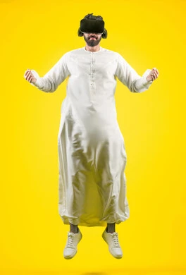 Enjoy watching movies and simulating the imaginary world, portrait of a young Emirati Gulf Arab man wearing a kandura and 3D VR glasses, interacting and merging with virtual reality games, jumping high and raising his fist to try to grab something, full body, yellow background