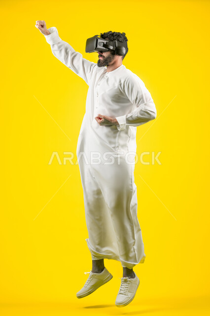 Mastering the art of boxing, enjoying watching movies and simulating the imaginary world, portrait of a young Arab Gulf Emirati man wearing a kandura and 3D VR glasses, interacting and merging with virtual reality games, jumping high and raising his fist with power gestures, full body, yellow background