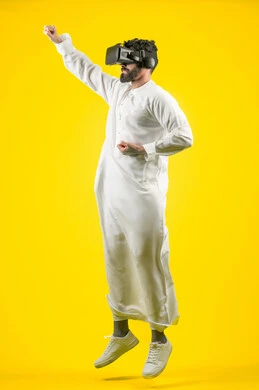 Mastering the art of boxing, enjoying watching movies and simulating the imaginary world, portrait of a young Arab Gulf Emirati man wearing a kandura and 3D VR glasses, interacting and merging with virtual reality games, jumping high and raising his fist with power gestures, full body, yellow background