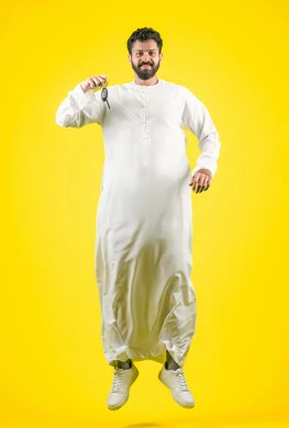 الحصول على رخصة القيادة، استلام وتسليم المفاتيح، القفز عاليا بإيماءات الحماس لامتلاك سيارة جديدة، خدمه صف السيارات بالمواقف الخاصه, بورتريه لشاب عربي خليجي اماراتي يرتدي الكندورة يمسك بيده مفتاح التحكم عن بعد, الجسم بالطول الكامل، خلفية صفراء
