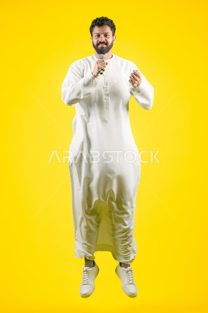 Integrating modern technologies and technology into practical life, communicating with family and friends, following the latest news and developments around the world, side portrait of a young Emirati Gulf Arab man wearing a kandura using a mobile phone, full body, yellow background