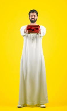 Giving gifts on holidays and special occasions, the concept of thanks and gratitude, looking at the camera with gestures of joy and happiness, expressing love, appreciation and respect, portrait of a young Emirati Gulf Arab man wearing a kandura holding a gift box, full body, yellow background