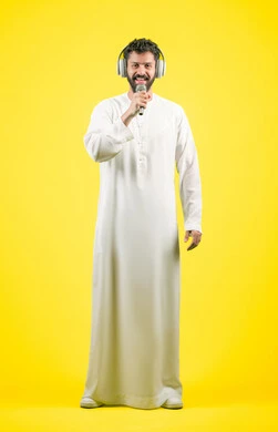 تسجيل مقطع صوتي غنائي، مواهب غنائية فنية، إيماءات السعادة و الاندماج مع الأغنية، بورتريه لرجل عربي خليجي اماراتي يرتدي الكندورة يضع سماعة الرأس ويقوم بالغناء باستخدام الميكروفون بتعابير الحماس, صورة الجسم بالكامل، خلفيه صفراء