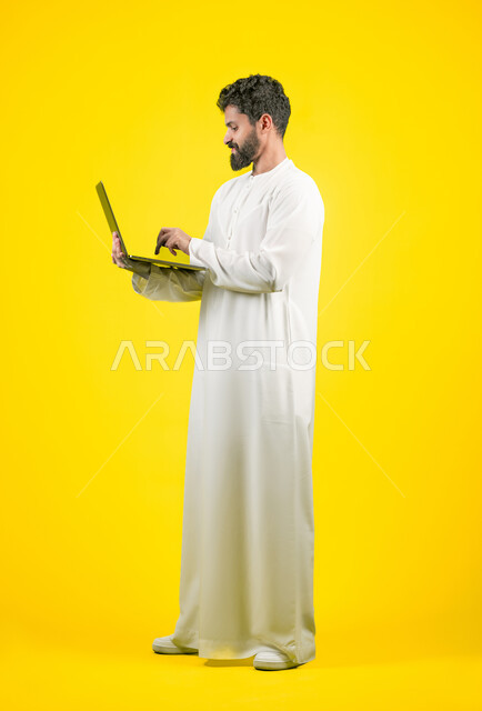 Using modern and advanced technology, using a laptop to complete remote work tasks, side portrait of an Emirati Gulf Arab man wearing a kandura using a computer with focus gestures, full body length, yellow background