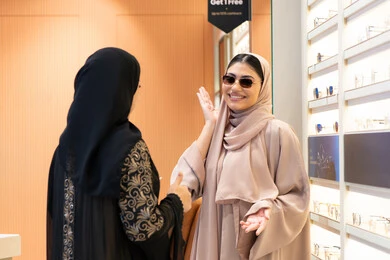 تعابير السرور والسعادة ، اختيار نظارة شمسيه مناسبة، احدث صيحات الموضة، صديقتان عربيتان خليجيتان سعوديتان ترتديان العباءة احداهما تقوم بقياس نظاره ، امرأة اماراتية تقوم بتجربة النظارات قبل الشراء، الاهتمام بالمظهر الخارجي،التأثير الإيجابي للتسوق على المرأة