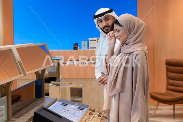 الاناقة والاهتمام بالمظهر الخارجي، اقتناء الاكسسورات من المولات ، مواكبة آخر صيحات الموضة والجمال، انواع وماركات عالميه ، زوجان عربيان خليجيان اماراتيان يقومان باختيار نظارة طبية ملائمة لملامح الوجه، المتعة بالتسوق في مولات الإمارات،مفهوم ضعف النظر