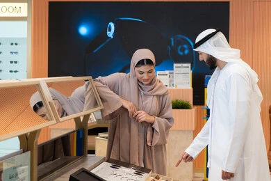 Keeping up with the latest fashion and beauty trends, buying accessories from malls, the concept of weak eyesight, global brands and types, enjoying shopping in UAE malls, elegance and attention to one's appearance, an Emirati Gulf Arab couple choosing eyeglasses that suit their facial features.