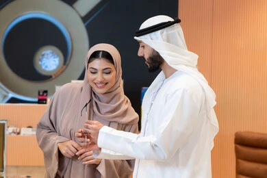 The concept of poor eyesight, buying accessories from malls, keeping up with the latest fashion and beauty trends, international brands and types, enjoying shopping in UAE malls, elegance and interest in one's appearance, an Emirati Gulf Arab couple choosing eyeglasses that suit their facial features.