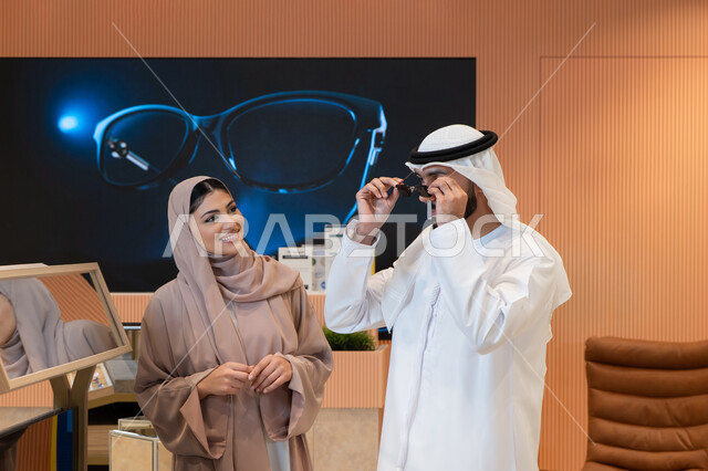 International brands and types, the pleasure of shopping in the UAE malls, keeping up with the latest fashion and beauty trends, elegance and attention to one's appearance, an Arab Gulf Emirati couple choosing sunglasses that suit their facial features, protecting their eyes from the sun's rays