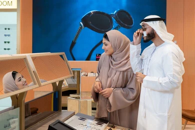 زوجان عربيان خليجيان اماراتيان يقومان باختيار نظارة شمسية ملائمة لملامح الوجه، حماية العينين من أشعة الشمس، الاناقة والاهتمام بالمظهر الخارجي، المتعة بالتسوق في مولات الإمارات، مواكبة آخر صيحات الموضة والجمال