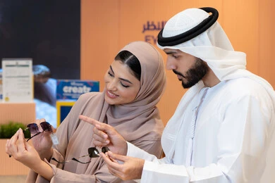 الاناقة والاهتمام بالمظهر الخارجي، المتعة بالتسوق في مولات الإمارات، مواكبة آخر صيحات الموضة والجمال، زوجان عربيان خليجيان اماراتيان يقومان باختيار نظارة شمسية ملائمة لملامح الوجه، حماية العينين من أشعة الشمس