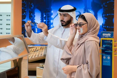 مواكبة آخر صيحات الموضة والجمال، حماية العينين من أشعة الشمس،الاهتمام بالمظهر الخارجي، المتعة بالتسوق في مولات الإمارات، زوجان عربيان خليجيان اماراتيان يقومان باختيار نظارة شمسية ملائمة لملامح الوجه