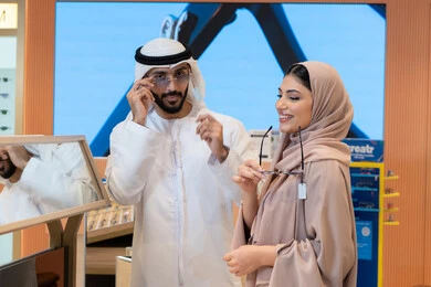 Protecting eyes from the sun's rays, keeping up with the latest fashion and beauty trends, taking care of one's appearance, enjoying shopping in the UAE malls, an Emirati Gulf Arab couple choosing sunglasses that suit their facial features