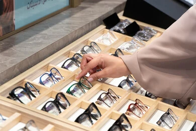 Eyeglasses corner, checking eyeglasses before buying, the joy of shopping and buying, a close-up of the hand of an Arab Gulf Emirati woman wearing an abaya choosing eyeglasses, the confusion in choosing suitable eyeglasses