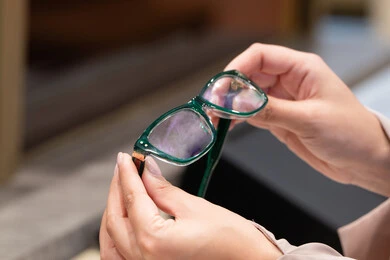 فحص النظارات الطبيه قبل الشراء، متعة التسويق والشراء ، صورة مقربة ليد امراه عربية خليجية اماراتية ترتدي العباءه تقوم باختيار نظاره طبيه، الحيرة في اختيار نظارة مناسبة