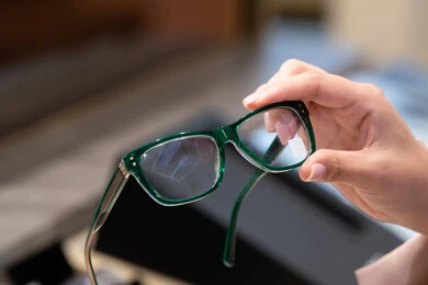 متعة التسويق والشراء ، صورة مقربة ليد امراه عربية خليجية اماراتية ترتدي العباءه تقوم باختيار نظاره طبيه، فحص النظارات الطبيه قبل الشراء،  الحيرة في اختيار نظارة مناسبة