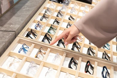 The joy of shopping and buying, checking eyeglasses before buying, a close-up of an Emirati Gulf Arab woman's hand wearing an abaya choosing eyeglasses, the confusion in choosing suitable eyeglasses