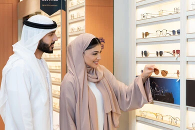 Shopping and buying from one of the UAE malls, the section dedicated to luxury sunglasses, attention to appearance and elegance, discounts and offers, an Arab Gulf couple from the UAE are choosing the suitable sunglasses in a UAE store.