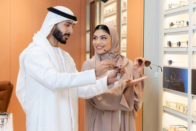 تخفيضات وخصومات وعروض، زوجان عربيان خليجيان اماراتيان يقومان باختيار النظارة الشمسيه المناسبة في محل اماراتي ، الركن الخاص بالنظارات الشمسيه الفخمه، التسوق والشراء من احدي المولات الاماراتيه، الاهتمام بالمظهر الخارجي والاناقه